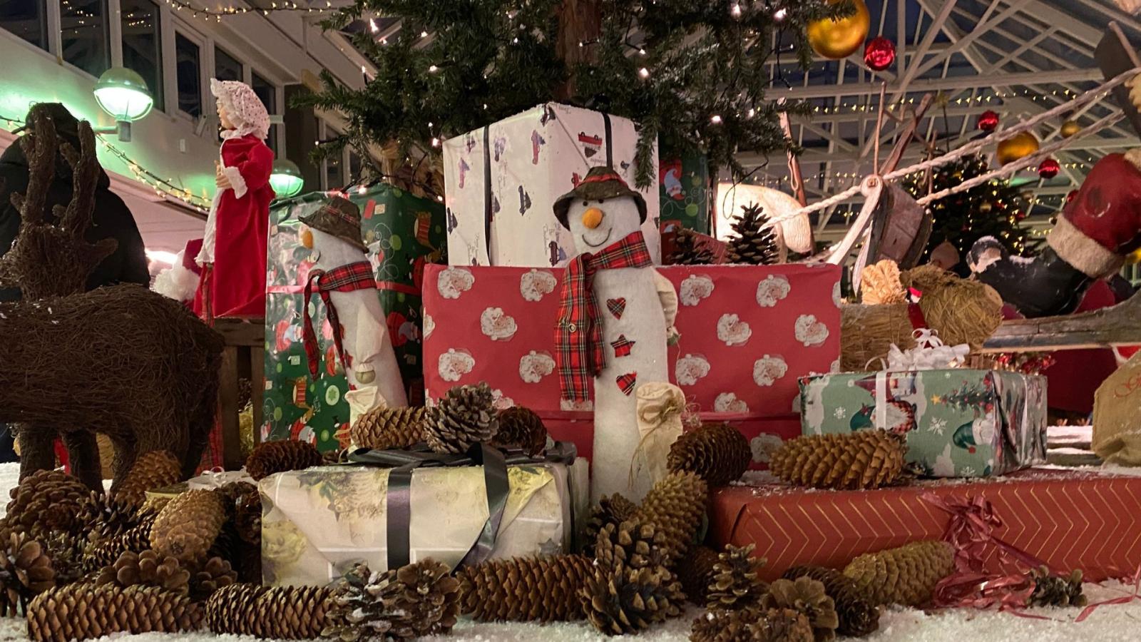 Foto af juleudstilling i Langeskov Centret med fokus på julegaver og en snemand i midten.