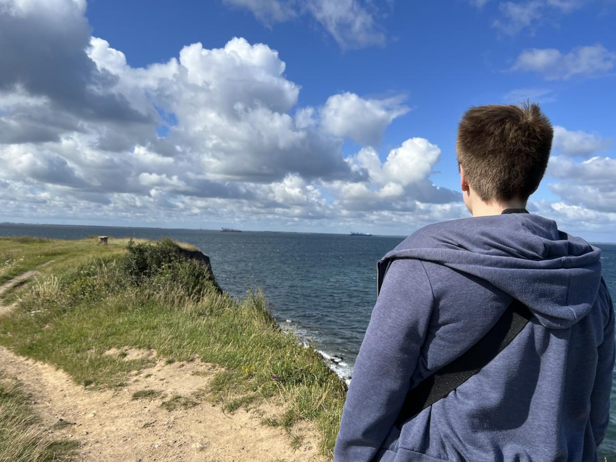 Person, der kigger ud over havet ved Fynshoved. Til venstre i billedet ses en sti.